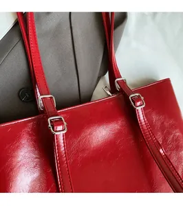 Detail of red glossy patent leather tote bag with silver metal buckles on handle