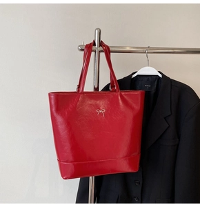 Detailed view of red PU leather tote bag with silver bow detail on a hanger