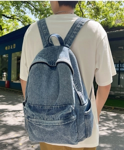 Rückansicht eines lässigen Denim-Rucksacks mit großer Kapazität, getragen von einem Studenten.