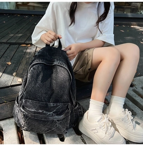 Outdoor view of a model with washed grey denim backpack featuring vintage street style
