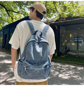 Blue washed denim backpack with large main compartment and front pocket worn by a model