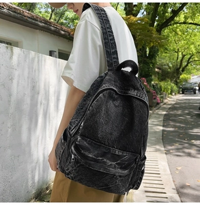 Detailed street-style shot of a vintage black washed denim backpack for travel