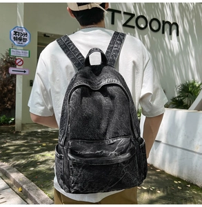 Outdoor view of a vintage acid wash black denim backpack with large capacity and zip pockets