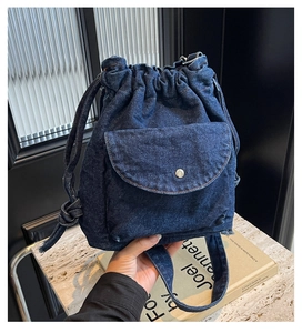 Detail eines dunkelblauen Denim-Kordelzug-Rucksacks mit Metallschnallentasche