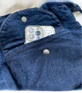 Detail einer blauen Denim-Beuteltasche mit Klapptasche, die ein Smartphone enthält