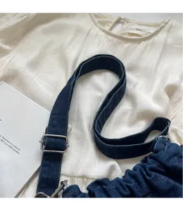 Detailansicht der dunkelblauen Denim-Beuteltasche mit Faltenstruktur und Metallschnalle