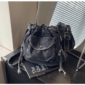 Detail einer schwarzen Denim-Beuteltasche mit Kontrastnähten und Kordelzug-Verschluss