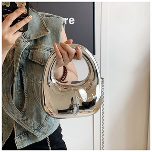 Detalle de bolso plateado efecto espejo con asa redonda hueca y cadena fina