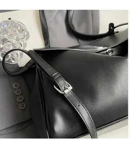 Detail of adjustable slender strap and silver hardware on lychee textured black bag