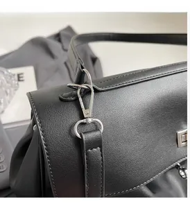 Detailed close-up of textured black leather handbag with polished silver metal clasp and hook