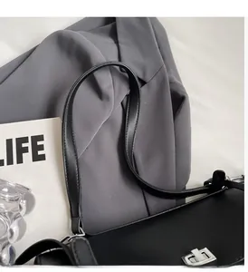 Detailed macro view of black leather shoulder bag with silver turn-lock and strap connector