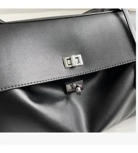 Detail of premium black leather tote with high-shine silver metal twist-lock clasp