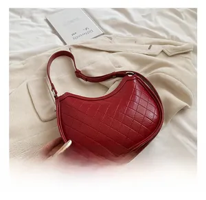 Detailed close-up of a red quilted semi-circle underarm bag in shiny patent leather finish