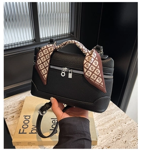 Detail of black lychee leather box bag with silk scarf wrapped handle and silver zippers