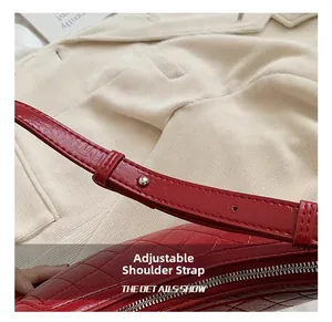Detail of adjustable shoulder strap and silver metal buckle on red quilted leather bag