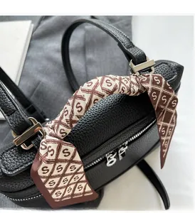 Close-up of black lychee grain leather bag with decorative logo-print silk scarf handle
