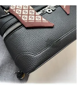 Close-up of black lychee grain leather bag with silver zipper and silk scarf handle