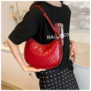 Detail view of a bright red crescent shoulder bag featuring quilted lattice pattern