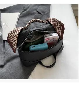 Detailed view of black litchi grain handbag showing large capacity and silk scarf handle
