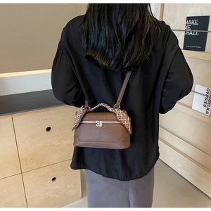 Detail of brown lychee grain leather handbag with a stylish silk scarf wrapped on the handle
