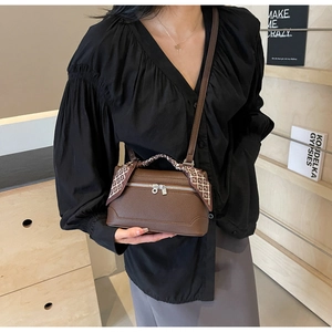 Detail of dark brown litchi leather bag with decorative silk scarf on handle