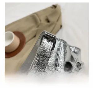 Détails du cuir texturé argenté avec coutures fines et boucle métallique du sac à main