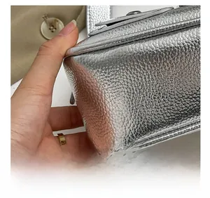 Détail de couture précise sur le sac à bandoulière en cuir grainé argenté au fini métallisé