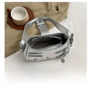 Vue intérieure détaillée du sac argenté à rivets avec poche zippée et pendentif étoile
