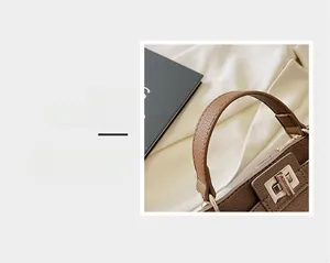 Macro detail of brown litchi pattern leather handle and golden metal twist lock closure