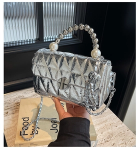 Detail of silver metallic quilted handbag with pearl handle and chain strap close-up