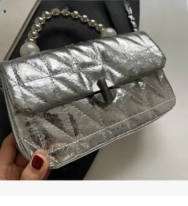 Detailed close-up of quilted silver handbag with pearl bead handle and metallic twist lock