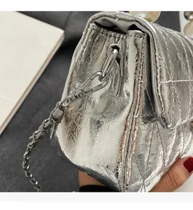 Detailed close-up of metallic silver quilted bag with large pearl handle and chain