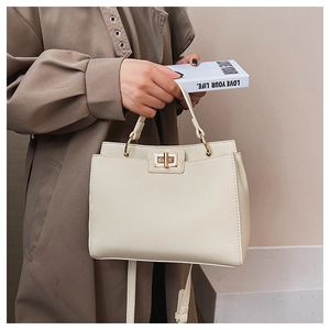 Close-up of cream pebble grain leather tote with a gold square twist lock and top handle