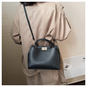 Detailed back view of a black lychee texture tote bag with gold hardware on a trench coat