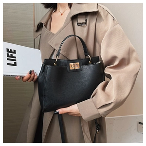 Detail of black lychee grain leather tote bag with gold metal twist lock and shoulder strap