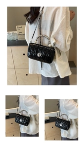 Detail of black quilted crossbody bag with pearl handle and silver twist lock