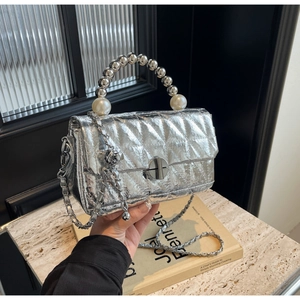 Detail of silver quilted handbag with pearl beaded handle and sleek metallic finish