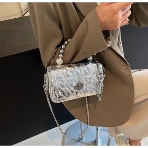 Close-up of silver quilted crossbody bag featuring a pearl and metal bead top handle
