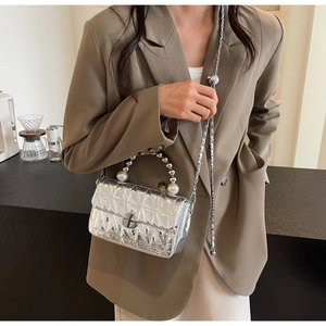 Close-up of quilted silver leather bag with elegant pearl handle and metal chain strap