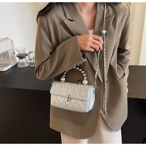 Detail of silver holographic quilted bag featuring pearl handle and metal chain strap