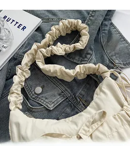Detail of soft cream fabric tote bag with pleated cloud strap on denim jacket