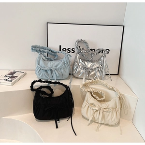 Close-up of pleated canvas dumpling bags with decorative bows and wide straps in four colors
