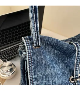 Detail of durable blue denim patchwork bag featuring silver metal rings and stitching