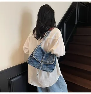Détail d'un sac bandoulière en jean vintage avec rabat et finition bleu délavé rétro