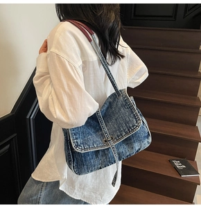 Detailed shot of a vintage denim shoulder bag worn over the shoulder by a model