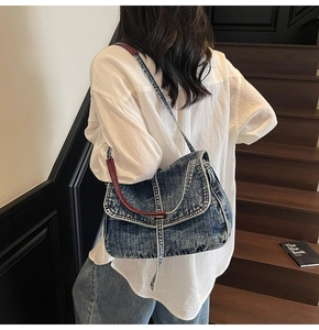 Detail of blue denim shoulder bag with red leather trim on model at a wooden staircase