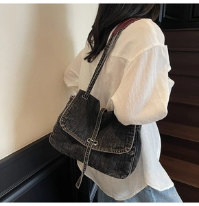 Close-up of vintage dark wash denim messenger bag showing textured fabric and metal buckle