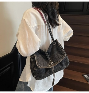 Detailed view of dark wash denim shoulder bag with leather strap and flap closure