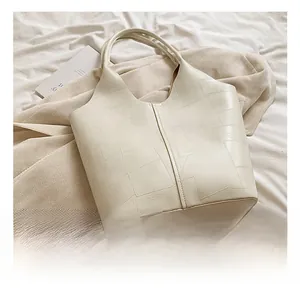 Vue macro des coutures géométriques sur le sac cabas en similicuir blanc cassé