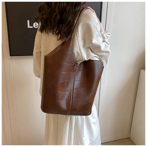 Détail du grand sac cabas marron foncé à texture matelassée porté à l'épaule